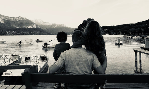 Un père avec sa fille et son fils sur un banc regardant les bateaux sur le lac et la montagne à Annecy