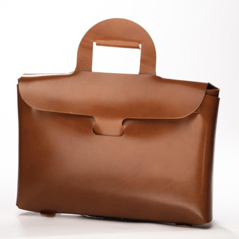 Cartable en cuir marron La Bouclée. Porte document en cuir fabriqué en France. Pochette en cuir ordinateur portable. Fabriqué d'une pièce de cuir sans couture, sans boutique. Cadeau original en cuir chez Robin concept store masculin, boutique en ligne de cadeau pour homme. Annecy, Lyon, Paris