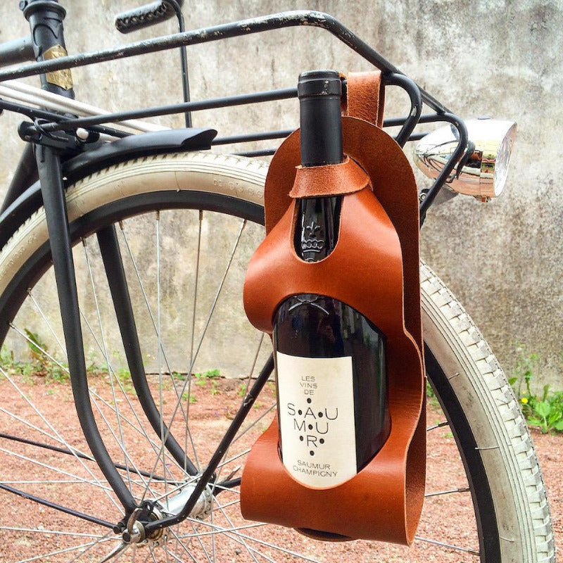 Sacoche pour transporter une bouteille de vin, de bière à vèlo idéal pour les picnics et les barbecues. Pochette en cuir pour bouteille. Accessoire de vélo en cuir. Porte bouteille en cuir cognac chez Robin concept store masculin, concept store homme, boutique en ligne de cadeau pour homme.