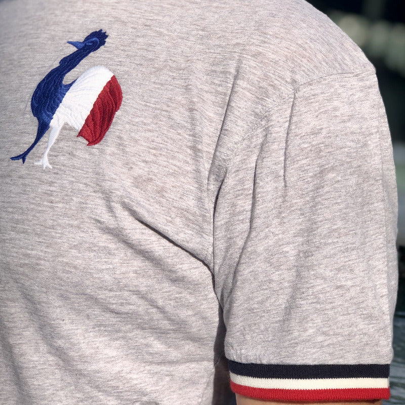Tee-shirt gris avec coq de l'embléme de l'équipe de France brodé sur la poitrine gauche avec bande tricolore sur les manche.
